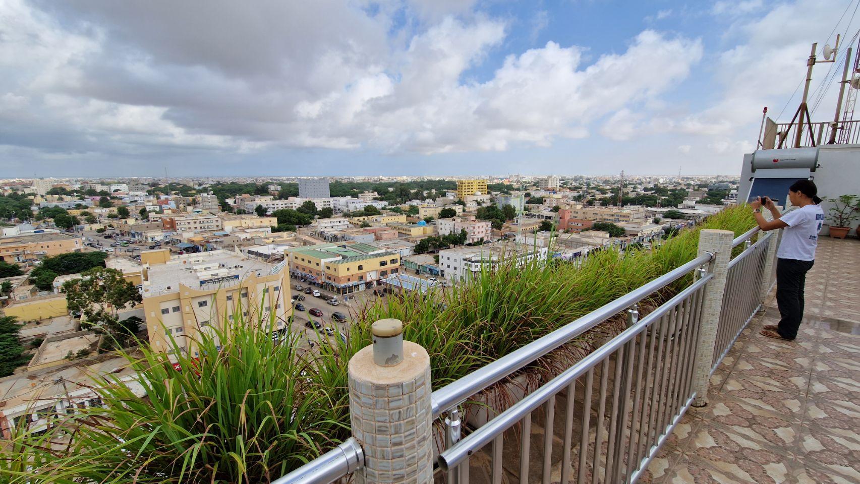 Max photographs the rooftops of Nouakchott, Mauritania, stretching toward the horizon from a rooftop terrace.