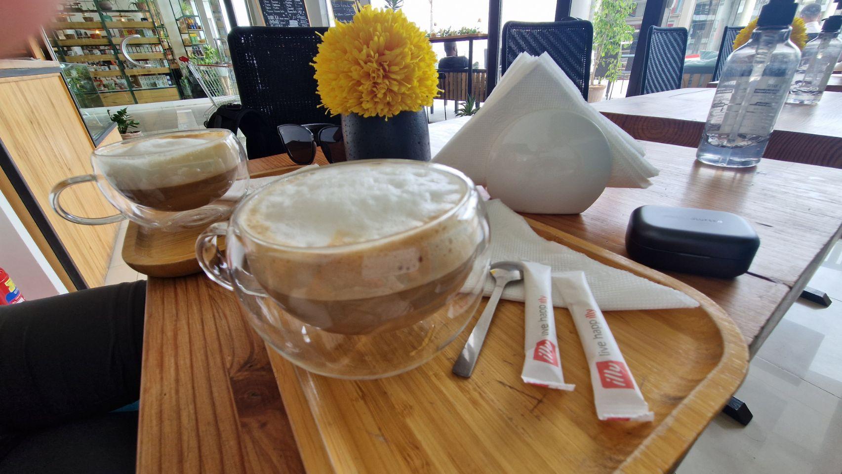 Two cappuccinos with thick milk foam sit on a wooden tray at a cafe table in Dakar.